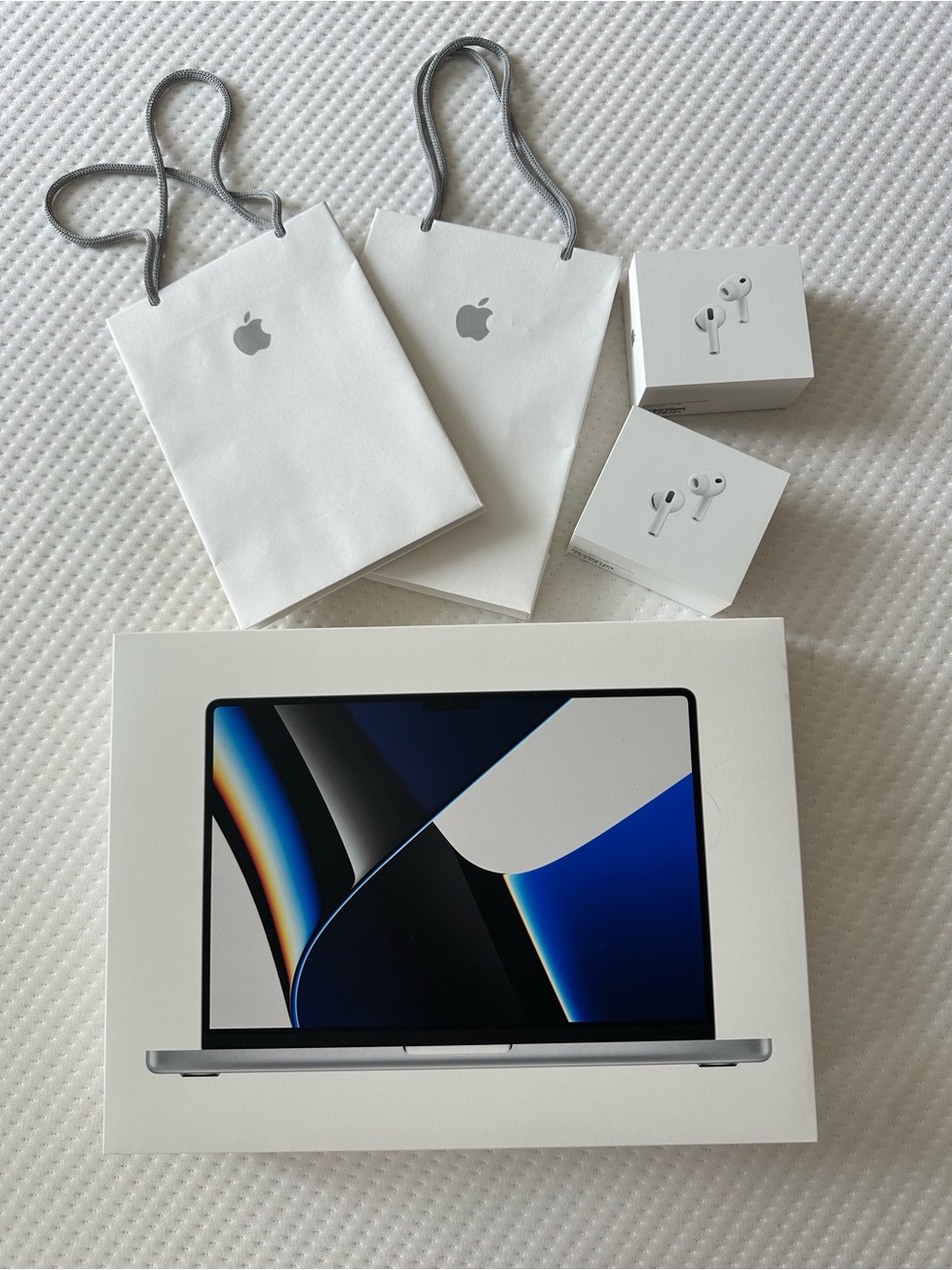Apple MacBook Pro and AirPods with White Apple Gift Bags